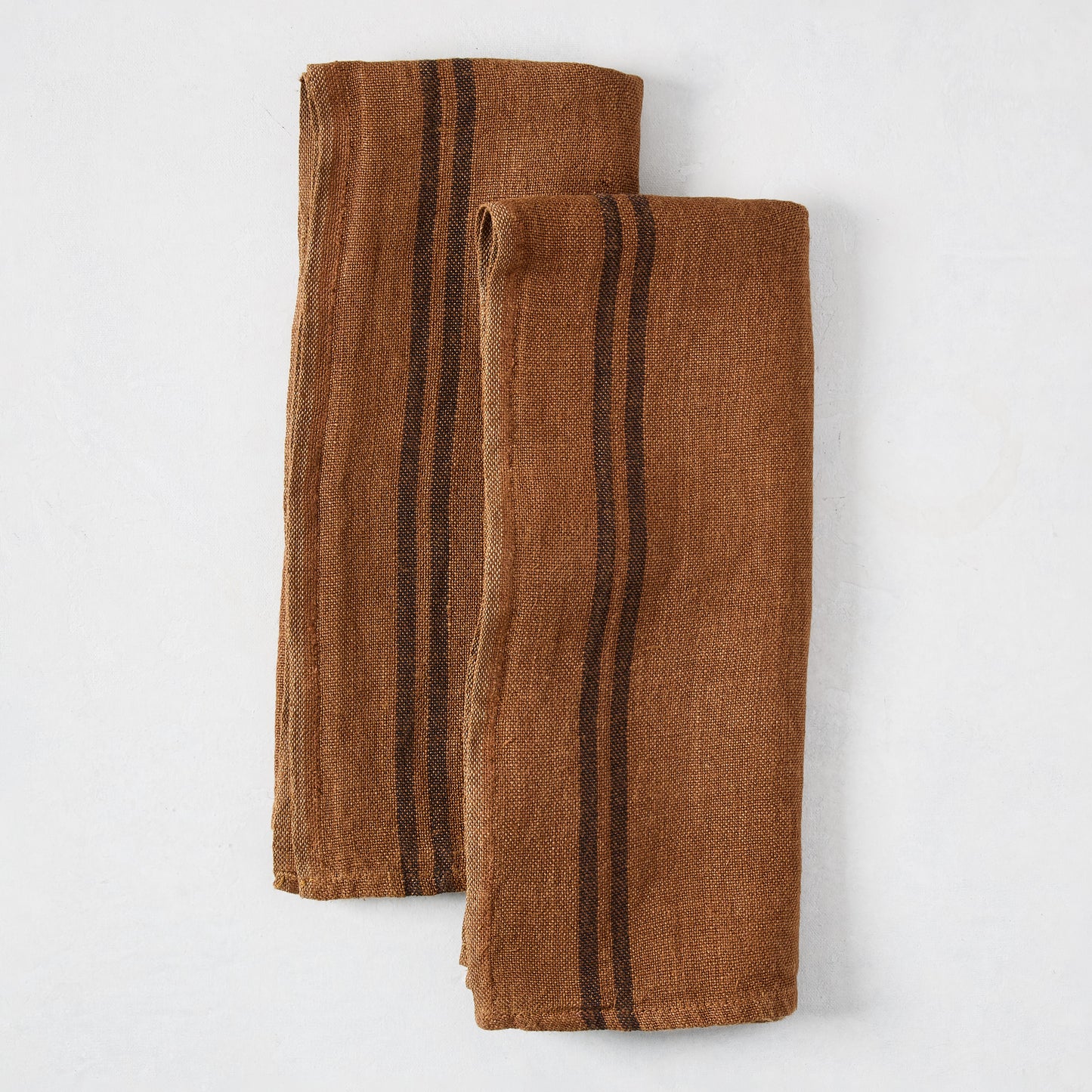 Set of 2 folded brown French linen hand towels with black stripes.