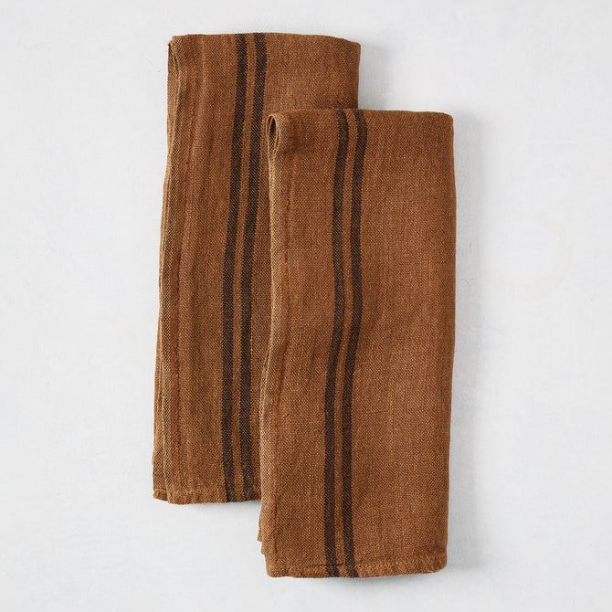 Set of 2 folded brown French linen hand towels with black stripes.