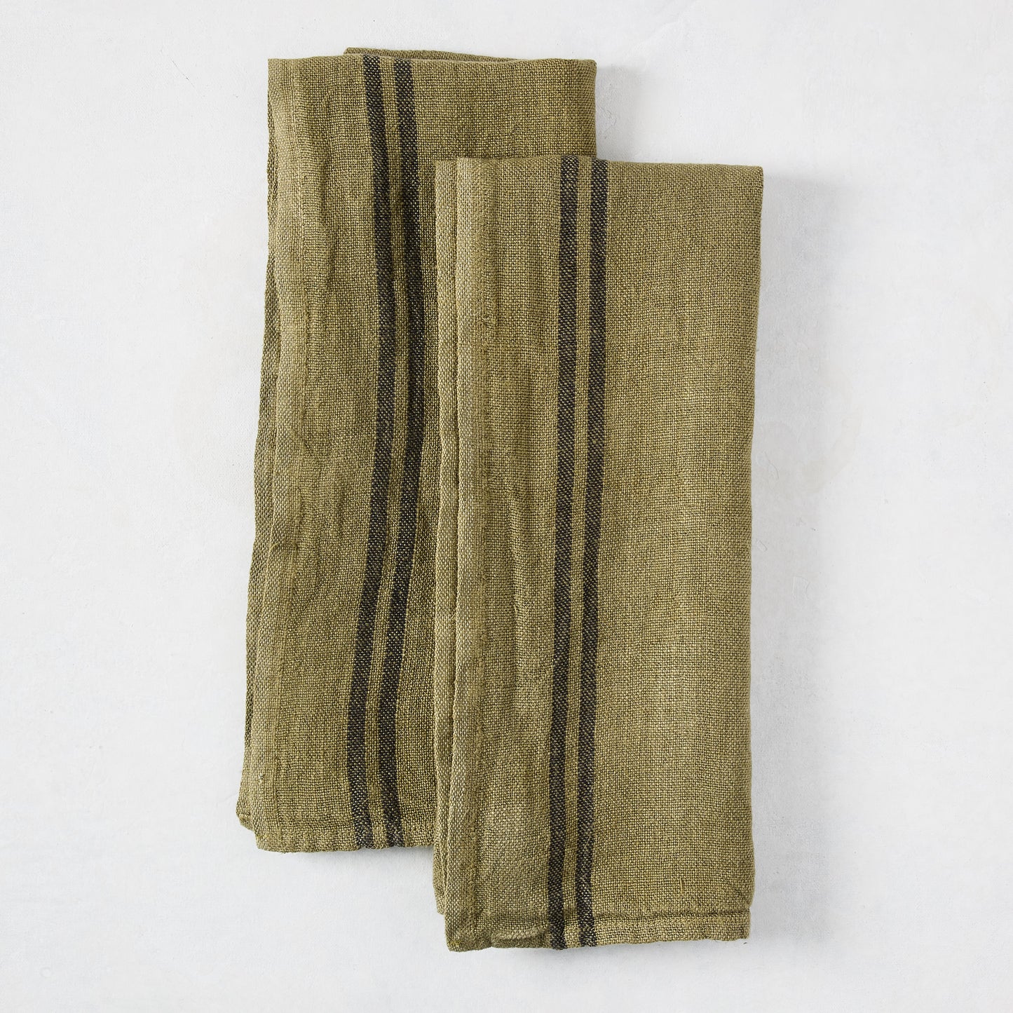 Set of two folded deep green French linen hand towels with black stripes.