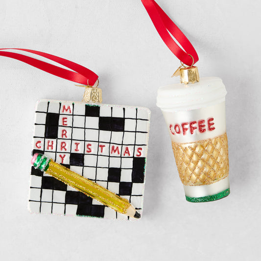 Glass Christmas ornaments featuring a square crossword puzzle with a pencil and a white coffee cup with a gold sleeve.