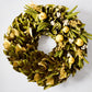 Sunlit Meadow Wreath with green magnolia leaves, chartreuse yellow pomegranates, and yarrow sprigs.