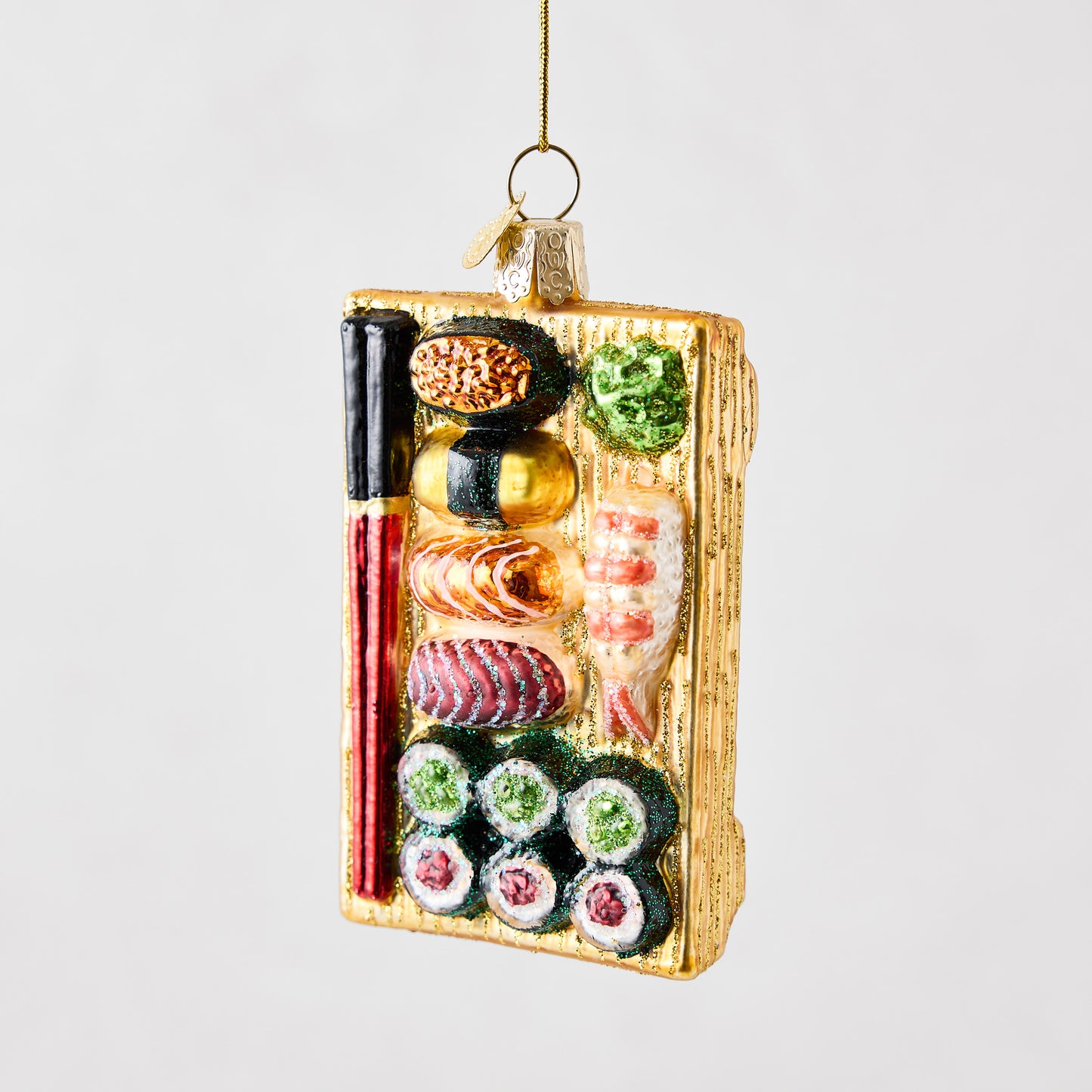 Hand-painted glass and resin sushi board Christmas ornament with glitter accents and red and black chopsticks.