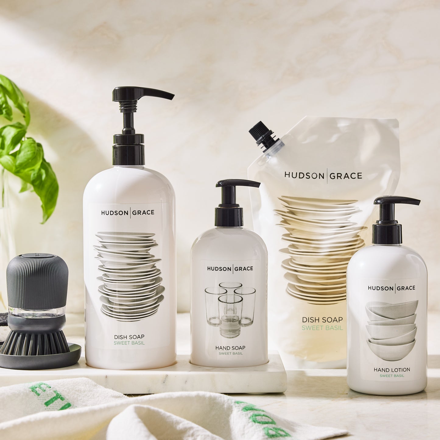 Hudson Grace Sweet Basil dish soap refill pouch, white bottles of dish soap, hand soap, and lotion.