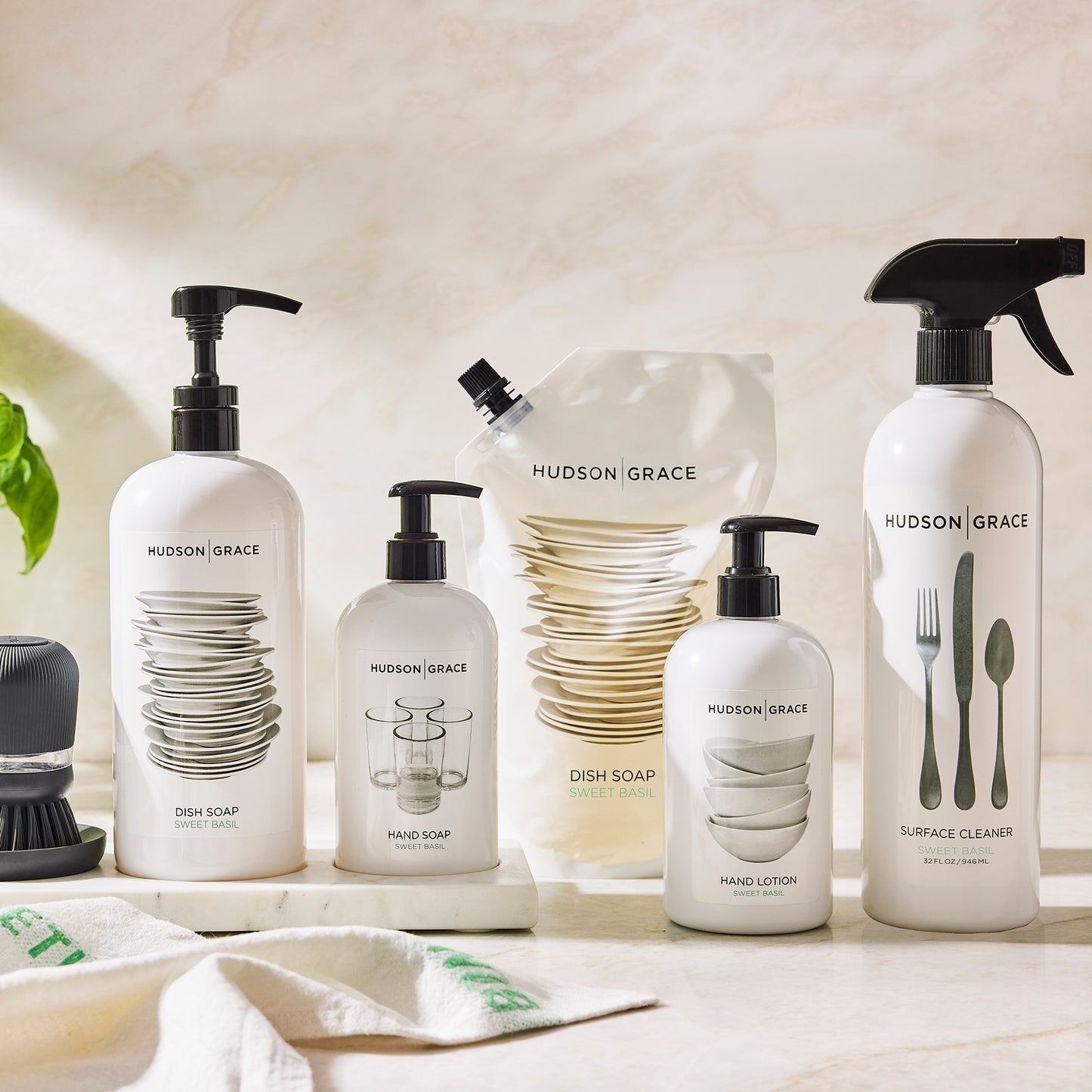 White Hudson Grace Sweet Basil dish soap, hand soap, hand lotion, and surface cleaner bottles with black pumps.