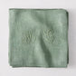 Folded Swiss Chard green antique French monogram napkin, linen-cotton blend, with embroidered "ML" initials.