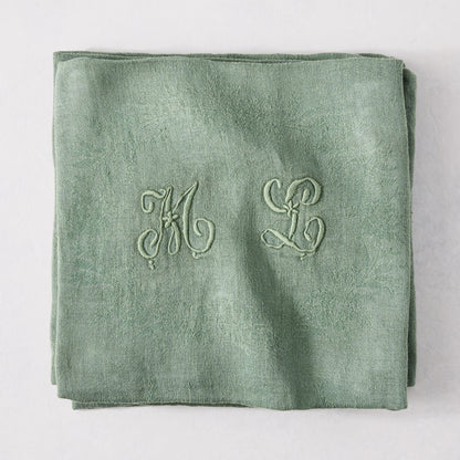 Folded Swiss Chard green antique French monogram napkin, linen-cotton blend, with embroidered "ML" initials.