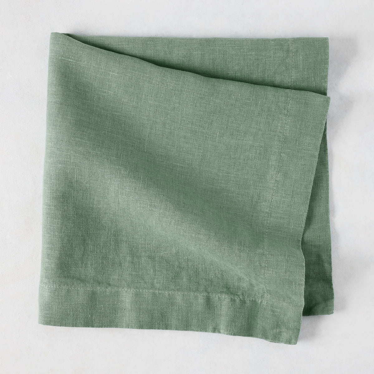 Swiss Chard HG Signature hand-dyed sage green linen napkin, folded, with visible texture and mitered corners.