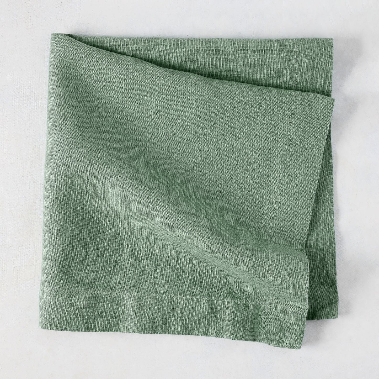 Swiss Chard HG Signature hand-dyed sage green linen napkin, folded, with visible texture and mitered corners.