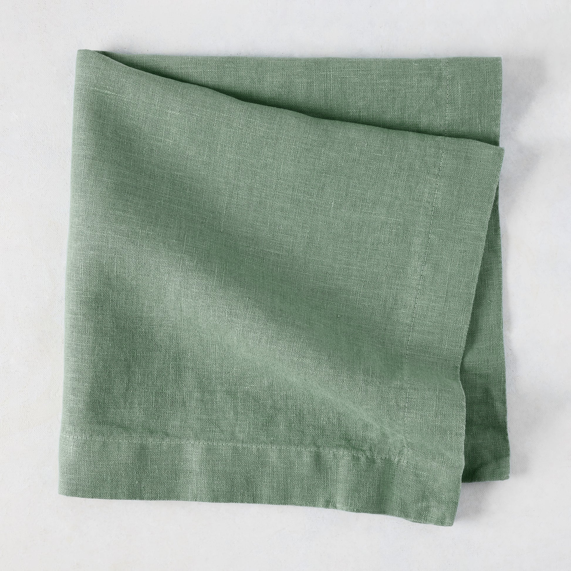 Swiss Chard HG Signature hand-dyed sage green linen napkin, folded, with visible texture and mitered corners.