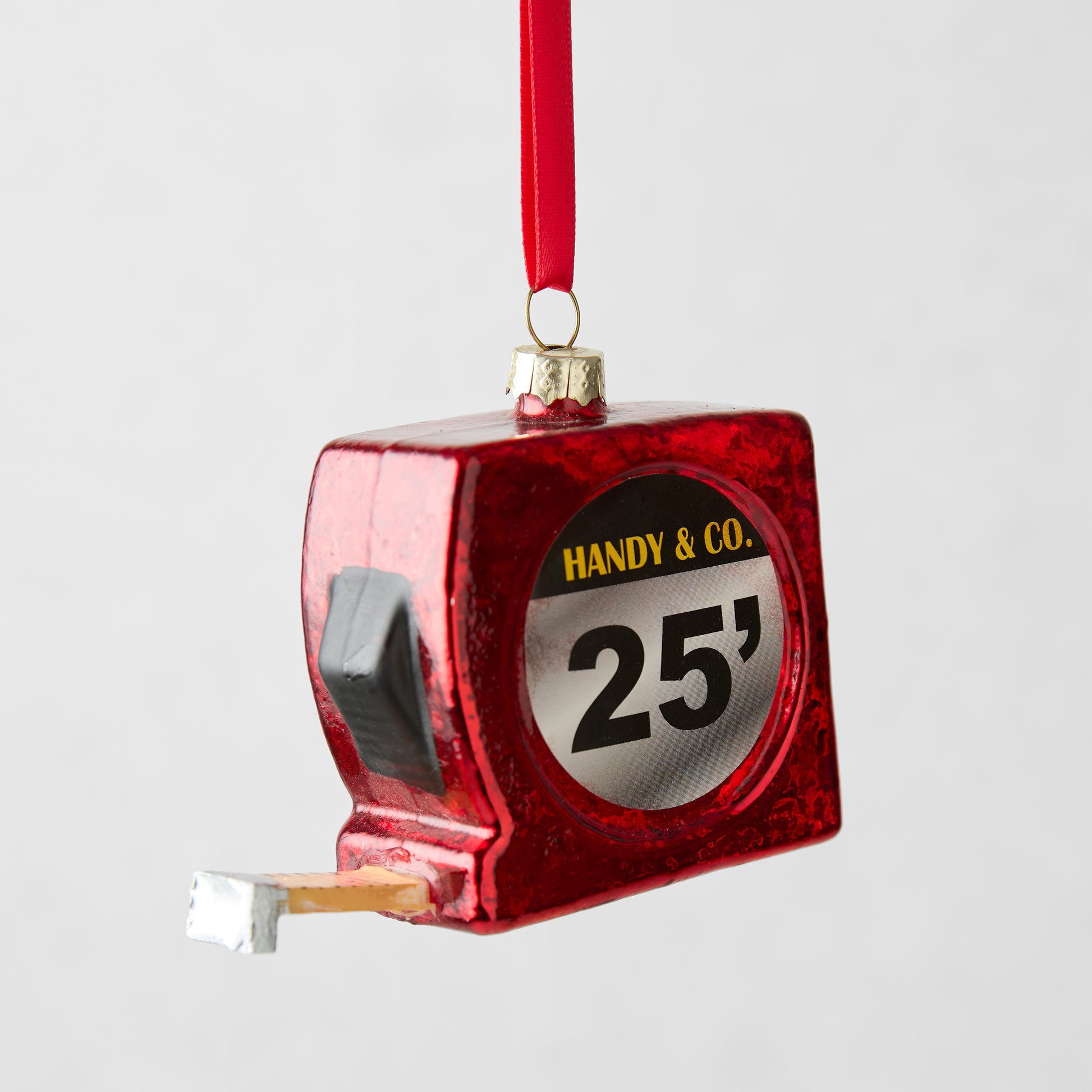 Red glitter glass tape measure Christmas ornament with "HANDY & CO. 25'" label.