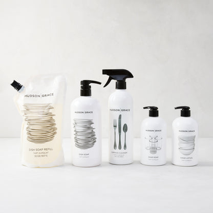 HG Tart Kumquat Dish Soap Refill Pouch, 32 oz, with white bottles of dish soap, cleaner, hand soap, and lotion.