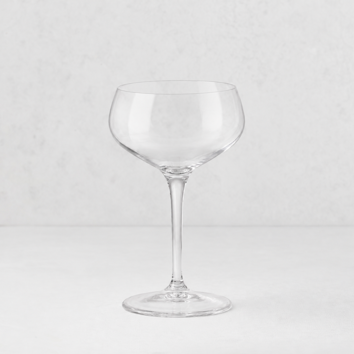 Clear glass Tavola coupe with a wide, shallow bowl and a slender stem on a white background.