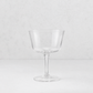 Clear glass coupe cocktail glass with a wide bowl and slender stem on a white background.