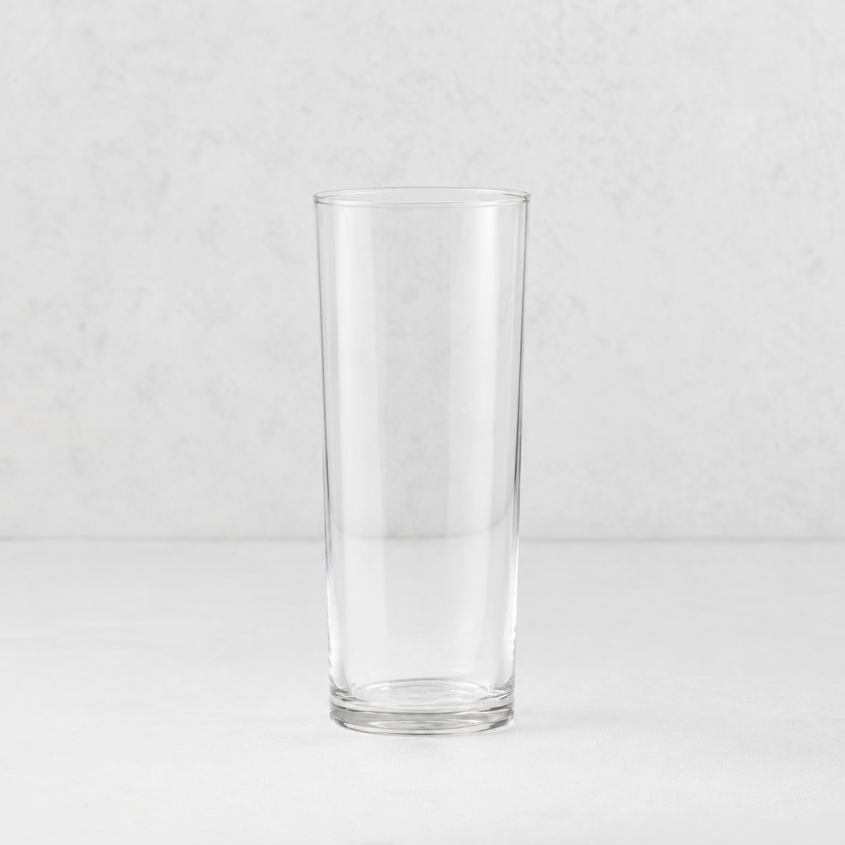 Tavola highball glass with a clear, cylindrical design and a sturdy base on a neutral background.