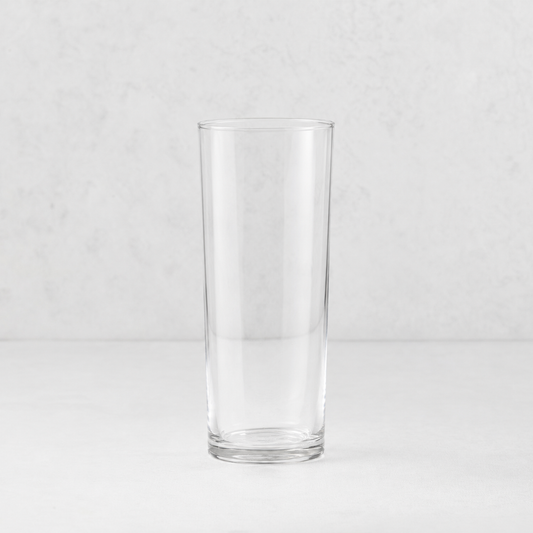 Tavola highball glass with a clear, cylindrical design and a sturdy base on a neutral background.