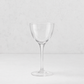 Clear glass Tavola Nic and Nora coup cocktail glass with a seamless stem and thin rim on a white surface.