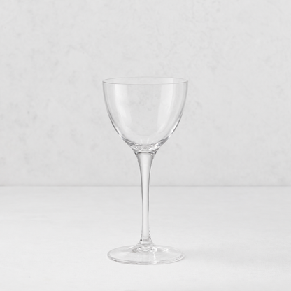 Clear glass Tavola Nic and Nora coup cocktail glass with a seamless stem and thin rim on a white surface.