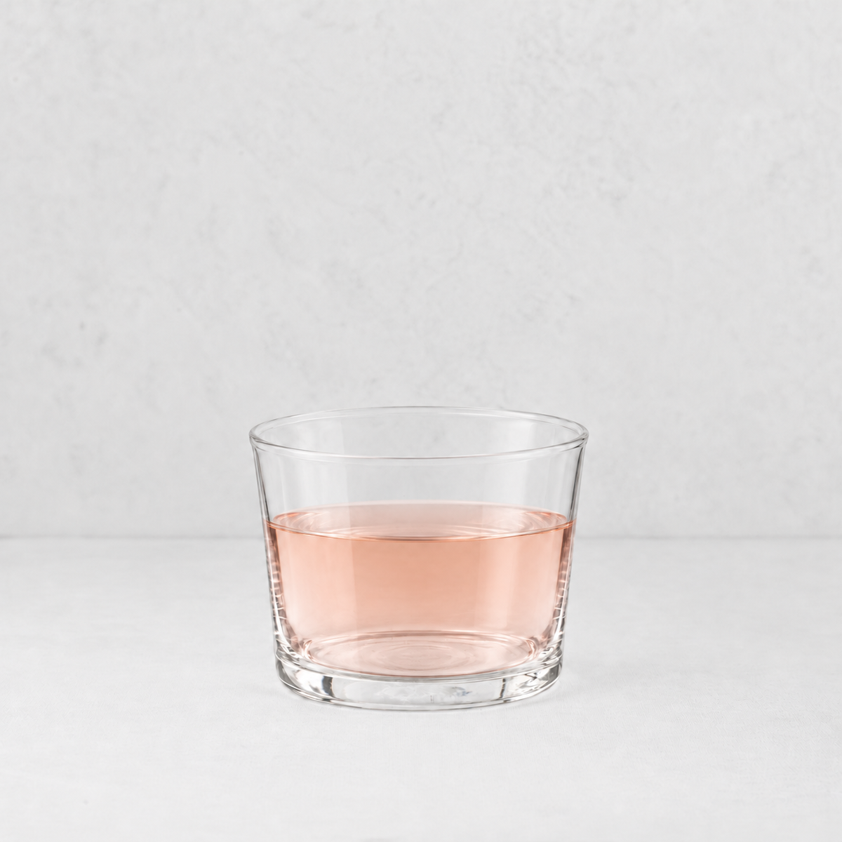 Mini Tavola tumbler in clear glass filled with a light pink liquid, set against a neutral white background.