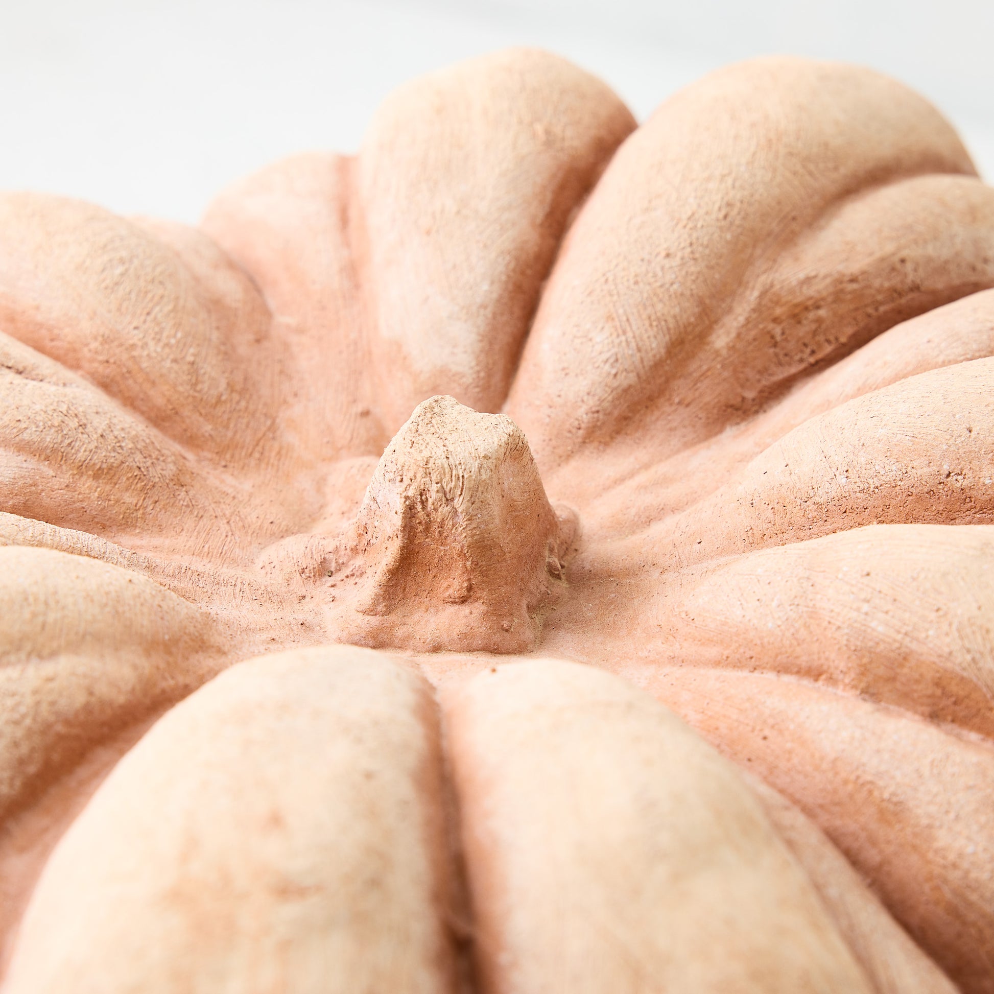 Close-up of a handcrafted terracotta pumpkin with a textured, matte finish and natural earthy orange tones.