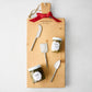 Wooden charcuterie board with red ribbon, silver cheese knives, Maison Marc mustard, and cornichons.