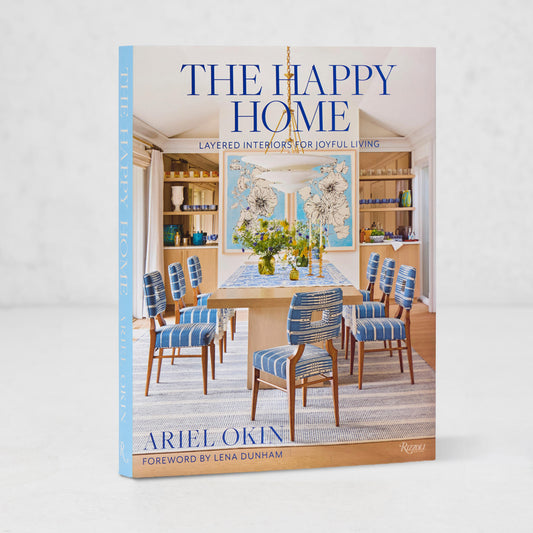 The Happy Home" hardcover book, light blue spine, featuring a bright dining room interior on the cover.