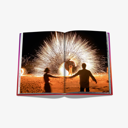 Open "Extraordinary Celebrations" book with a vibrant fire show photo spread, red matte hardcover.