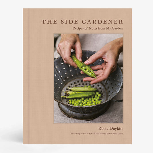 Hardcover book, "The Side Gardener," with a tan cover featuring hands shelling peas into a metal colander.