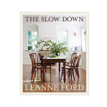 The Slow Down" hardcover book, featuring a rustic kitchen interior with a wooden table and chairs.
