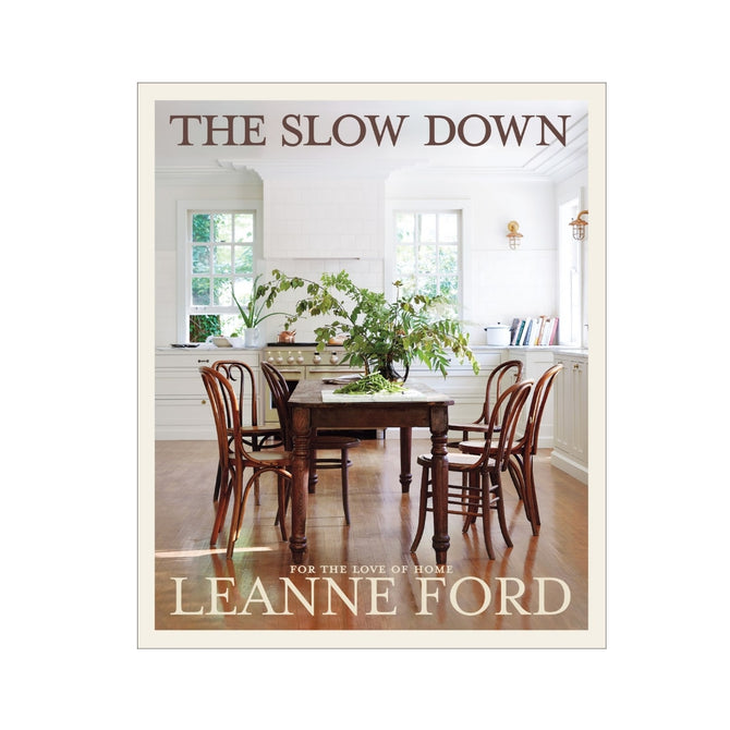 The Slow Down" hardcover book, featuring a rustic kitchen interior with a wooden table and chairs.