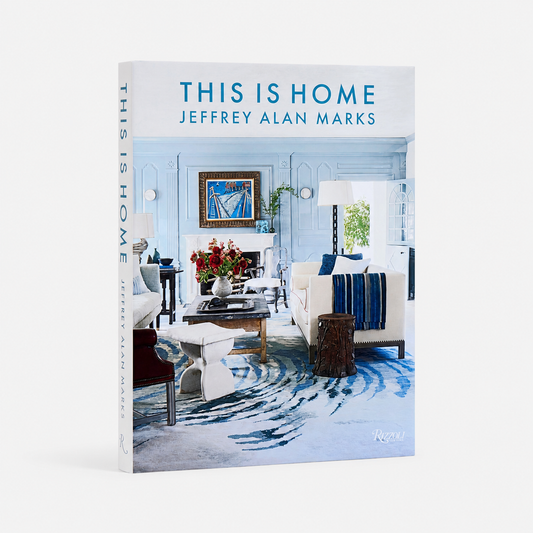 This Is Home: Jeffrey Alan Marks book cover and spine, featuring a bright blue-and-white living room interior photograph with blue title text at the top, shown on a light gray background.