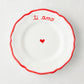White ceramic appetizer plate with red "ti amo" text, heart, and ruffled border.