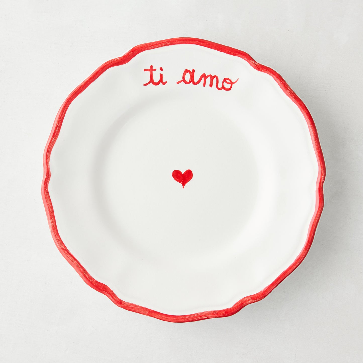 White ceramic appetizer plate with red "ti amo" text, heart, and ruffled border.