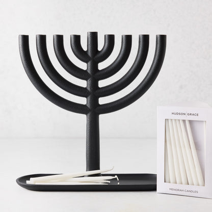 Black cast-iron Hanukkah menorah with a box of 45 slim, white unscented paraffin taper candles.