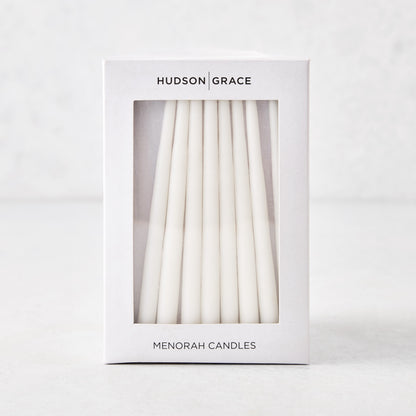 Box of 45 slender, hand-dipped white paraffin Hanukkah taper candles in white Hudson Grace packaging.
