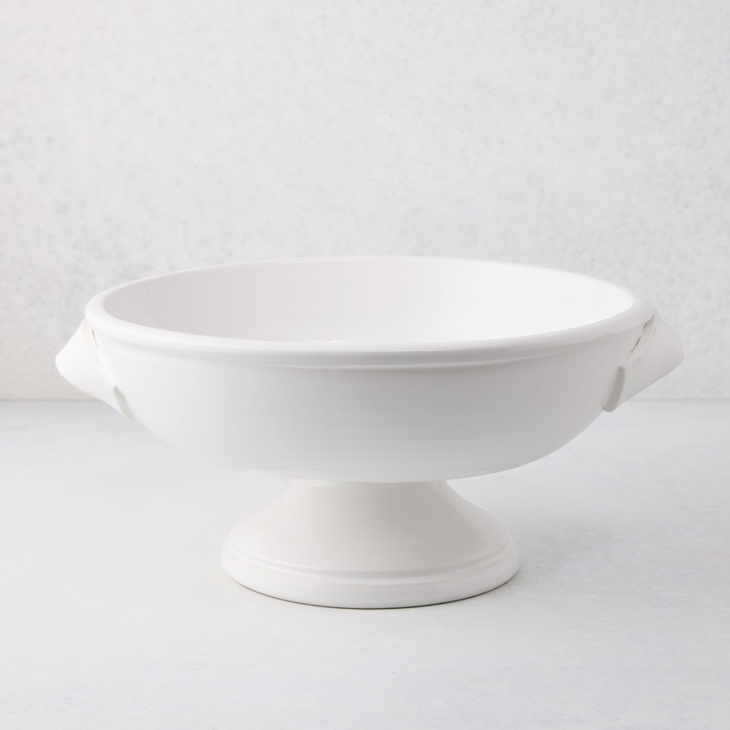 Tivoli white ceramic pedestal serve bowl with two handles, 15.3"L x 13.3"W x 6.7"H.