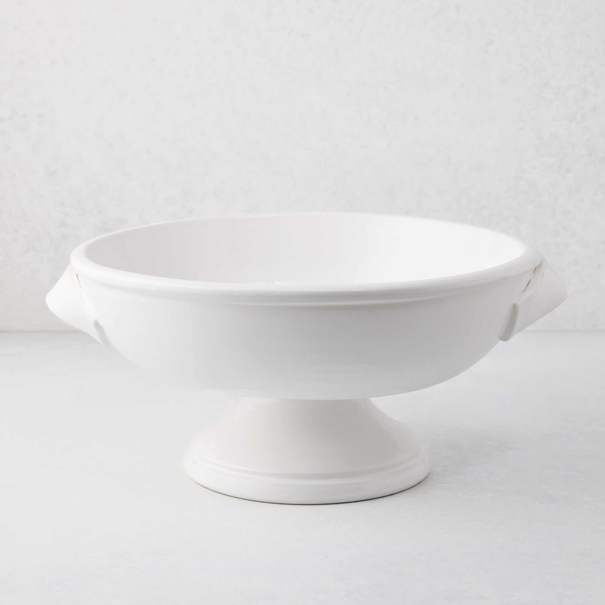 Tivoli white ceramic pedestal serve bowl with two handles, 15.3"L x 13.3"W x 6.7"H.