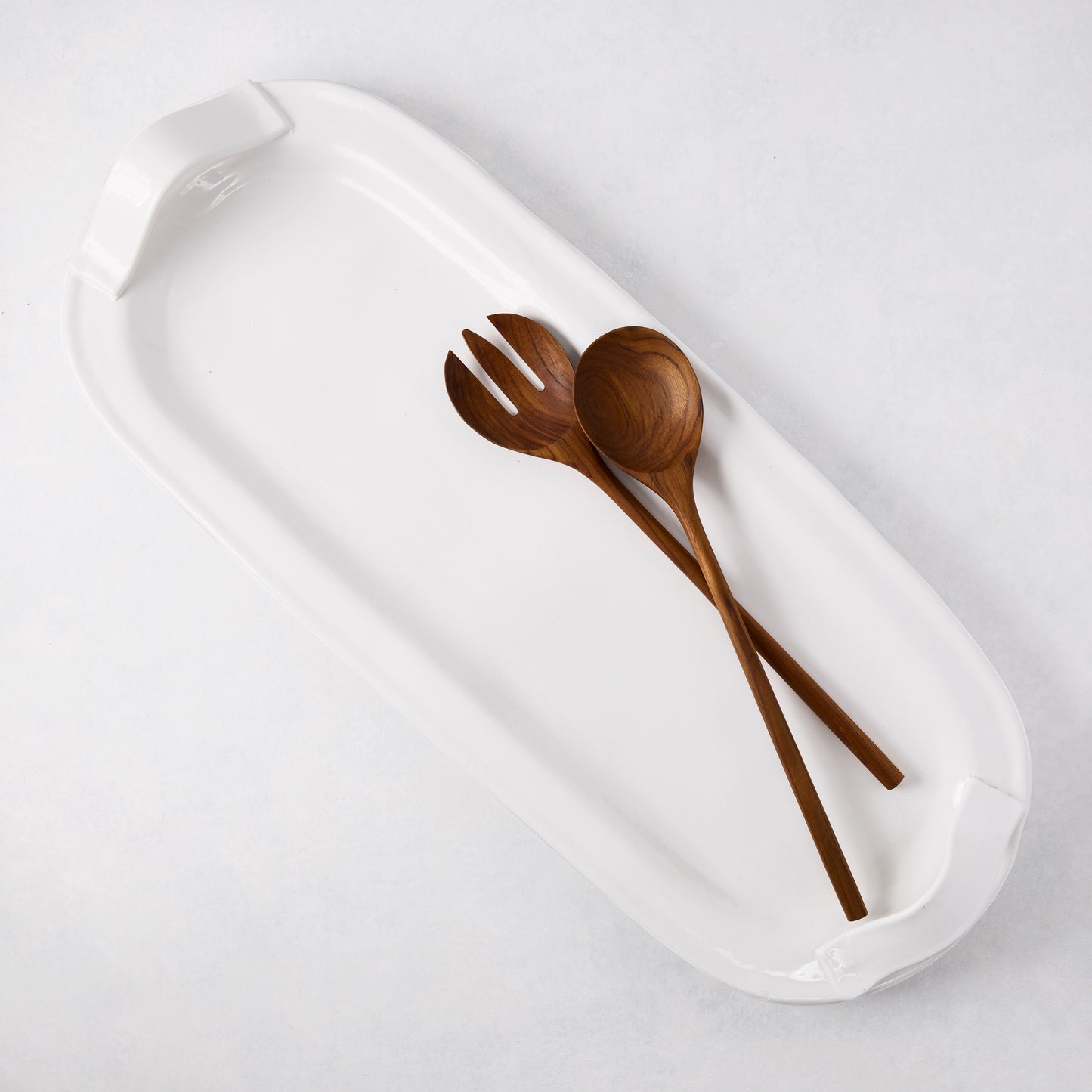 30-inch white ceramic rectangular serving platter with a pair of long teak wood salad servers.