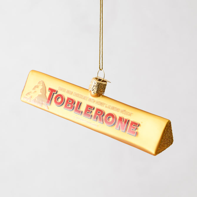 Hand-painted glass Toblerone chocolate bar Christmas ornament with gold glitter accents and a hanging loop.