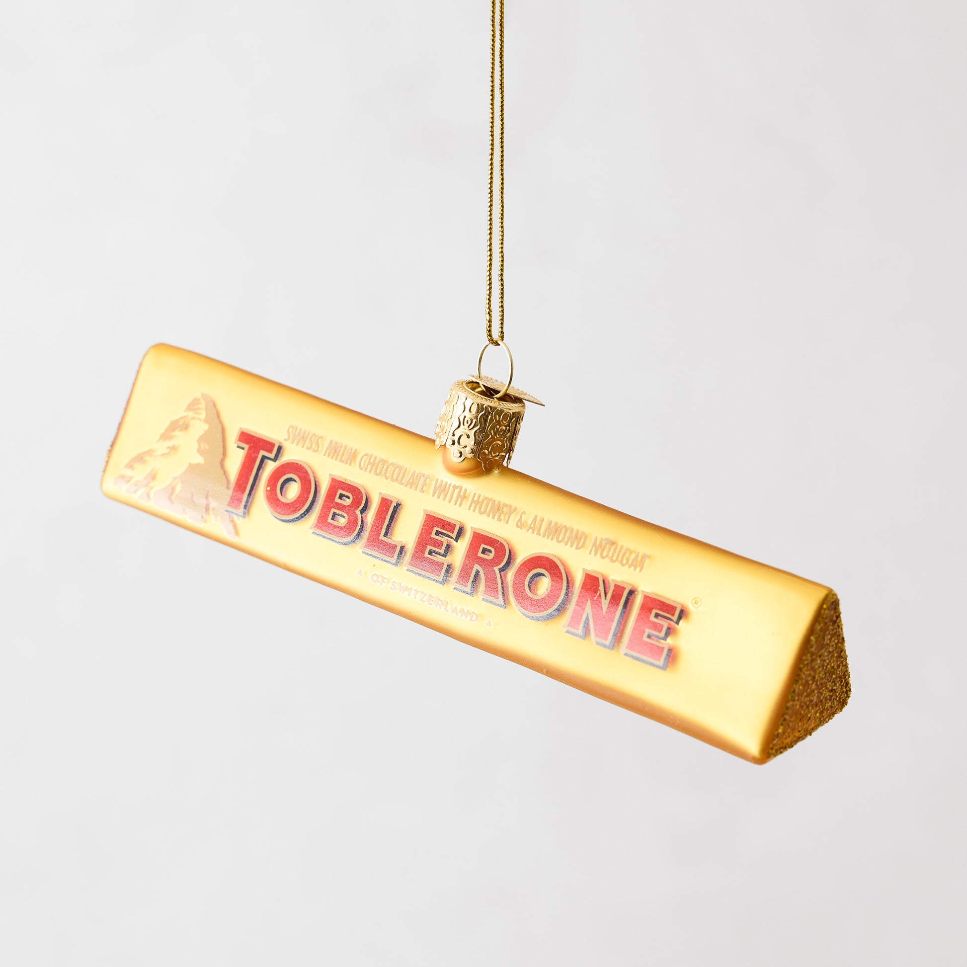 Hand-painted glass Toblerone chocolate bar Christmas ornament with gold glitter accents and a hanging loop.
