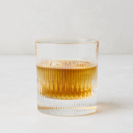 Tratto Ribbed Eco-Crystal Old Fashioned Glass with amber liquid and ice.