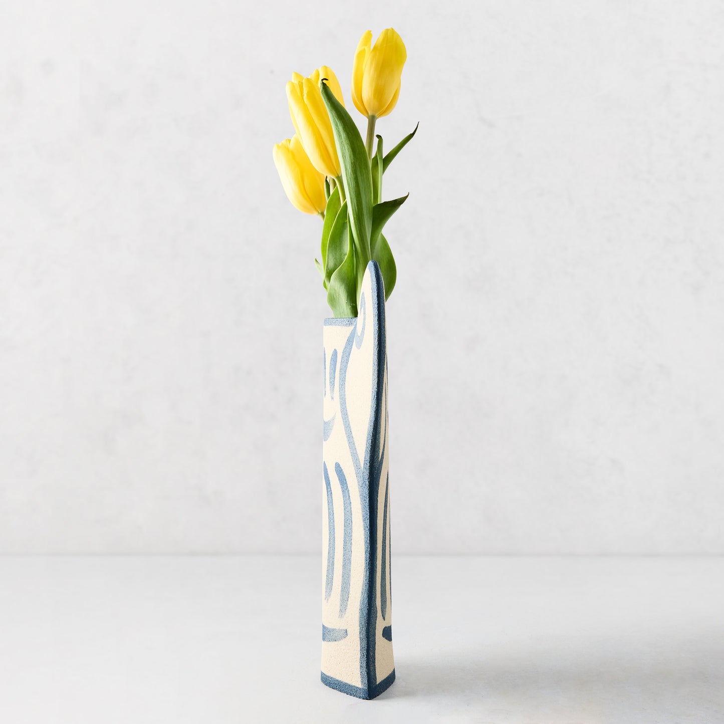 Trompe-L'oeil Greek Coupe Krater stoneware vase with blue detailing, holding yellow tulips.