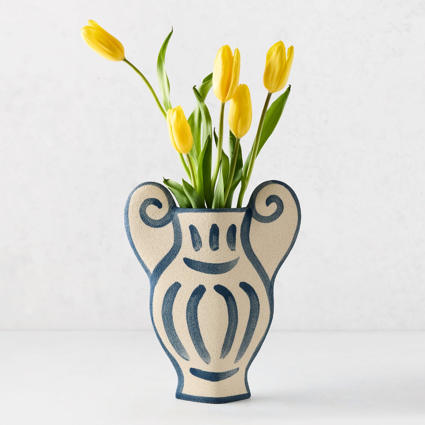 Trompe-L'oeil N1 Krater stoneware vase, 12.6"H, with raw texture and hand-painted blue Greek-inspired detailing, holding yellow tulips.