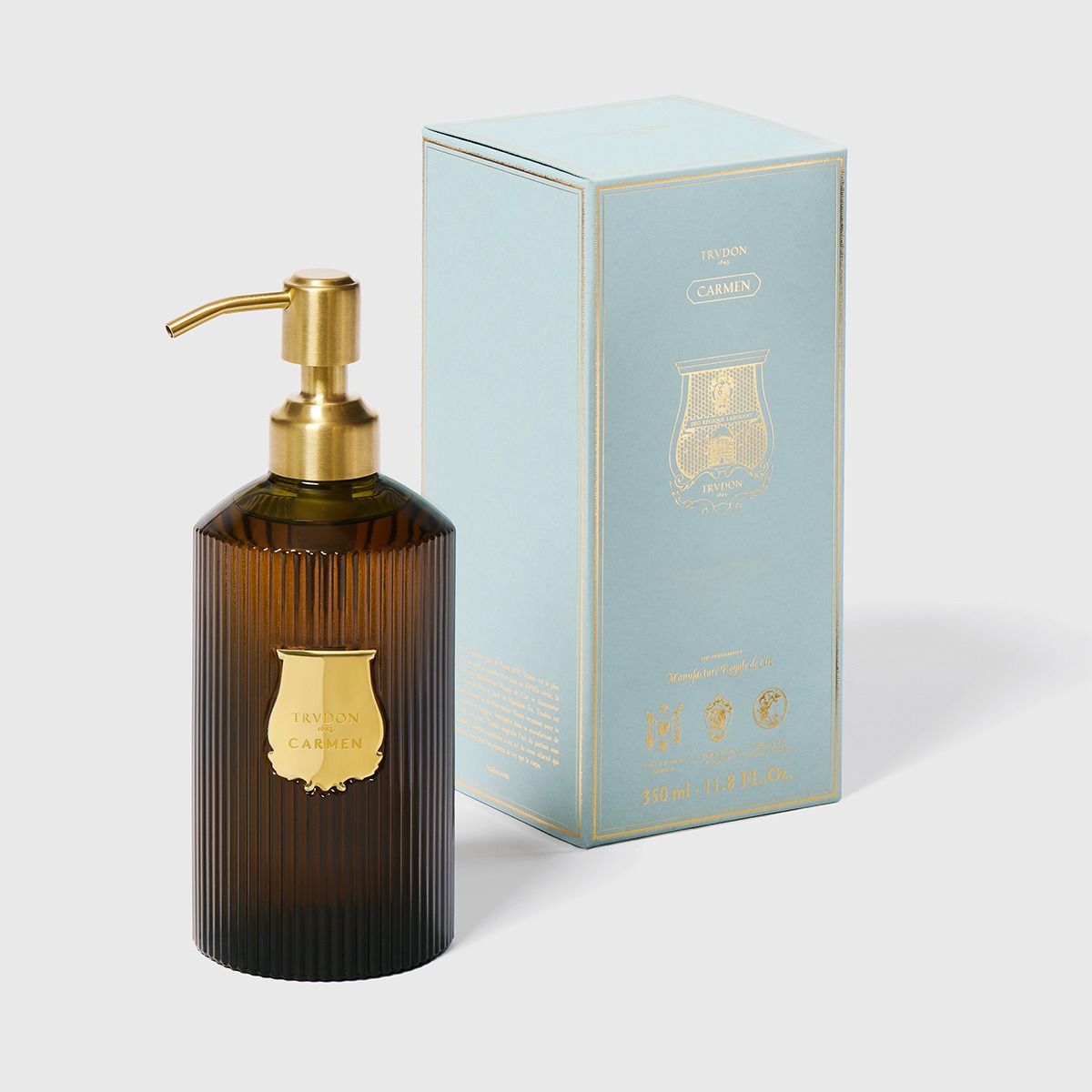 Trudon Carmen liquid hand soap in a ribbed dark amber glass bottle with a gold pump and label, beside a light blue box.