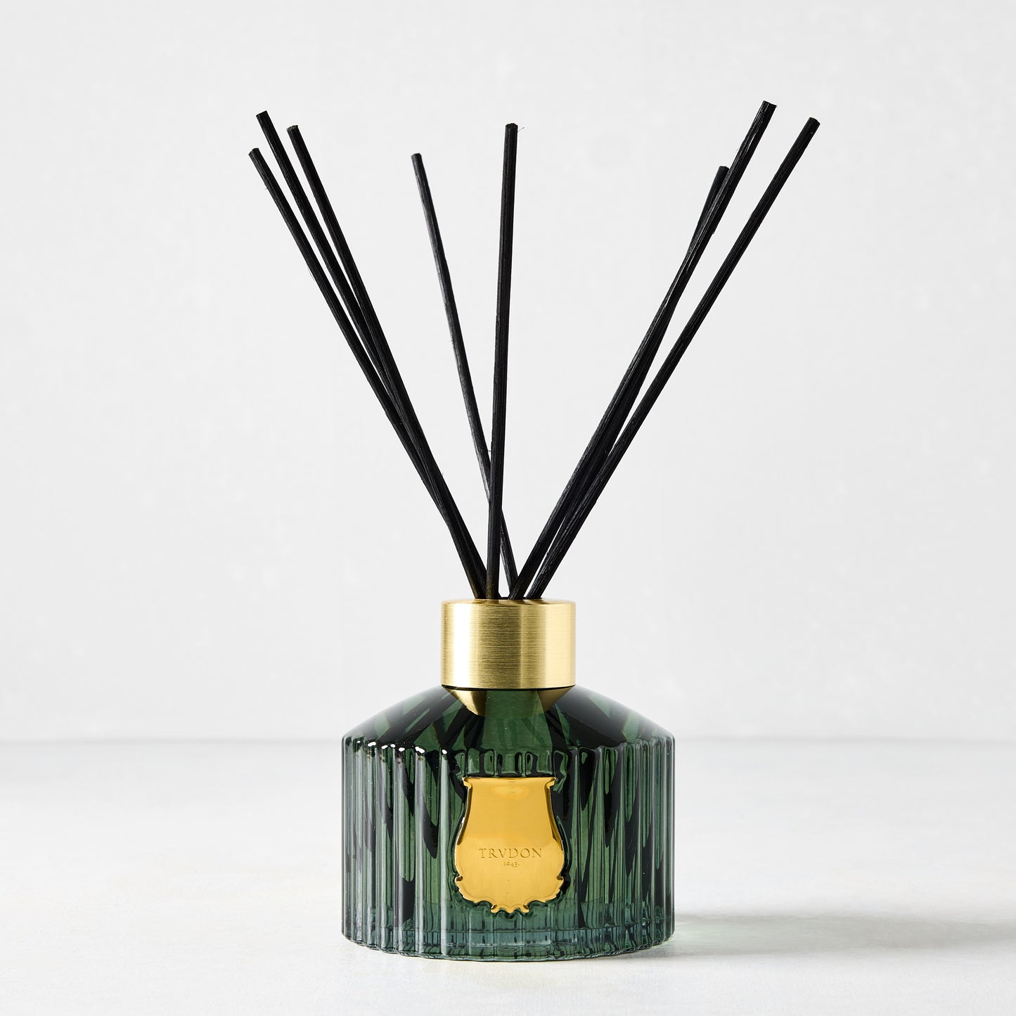 Trudon Figuerie Scented Reed Diffuser: dark green fluted glass, gold seal, black rattan sticks.