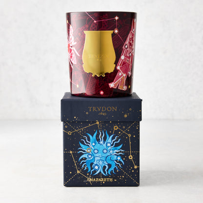 Trudon Nazareth Holiday Edition scented candle in a red and gold illustrated glass vessel, on a dark blue box.