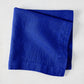Ultramarine HG Signature hand-dyed 22" square linen napkin, folded, on a white background.
