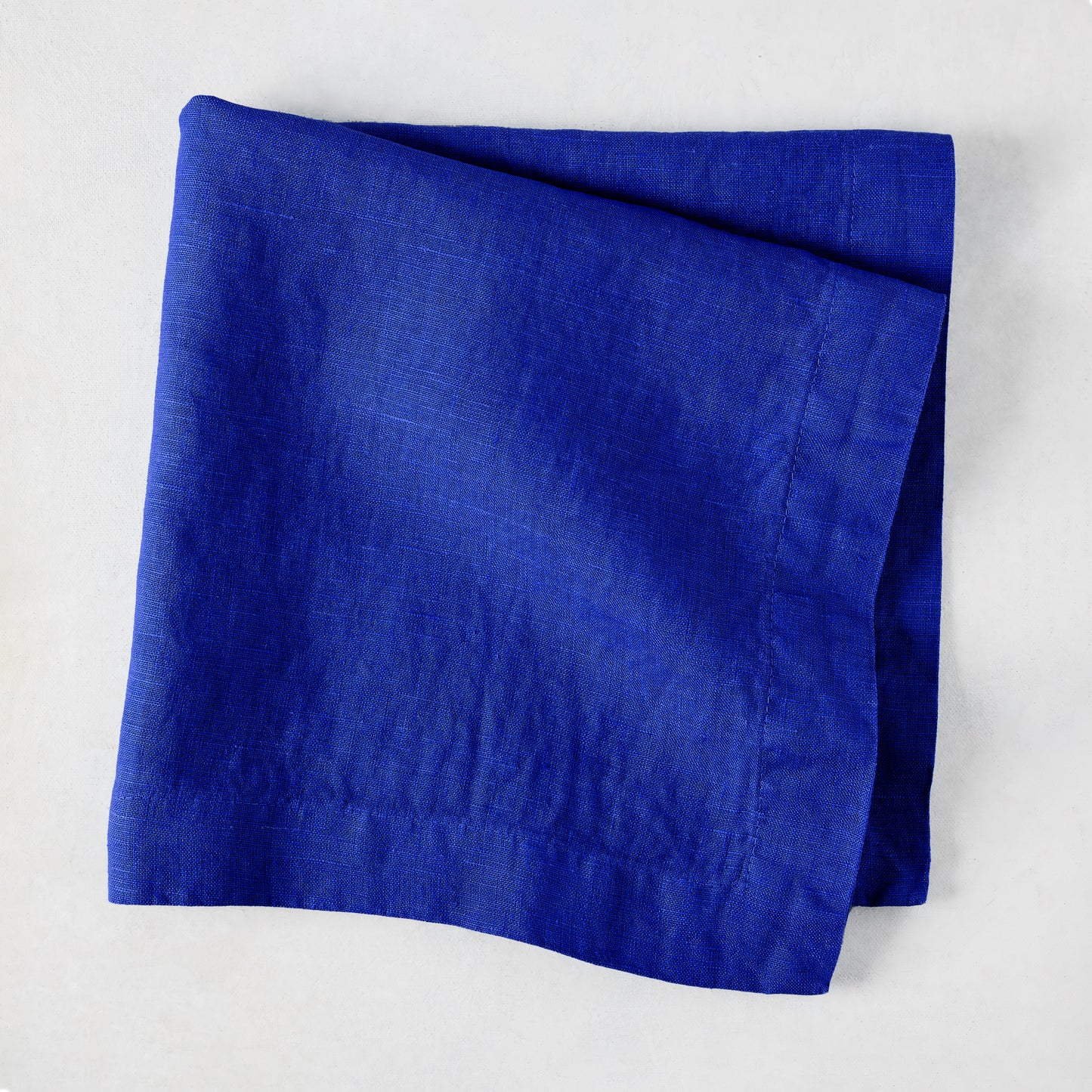 Ultramarine HG Signature hand-dyed 22" square linen napkin, folded, on a white background.