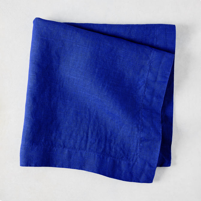 Ultramarine HG Signature hand-dyed 22" square linen napkin, folded, on a white background.