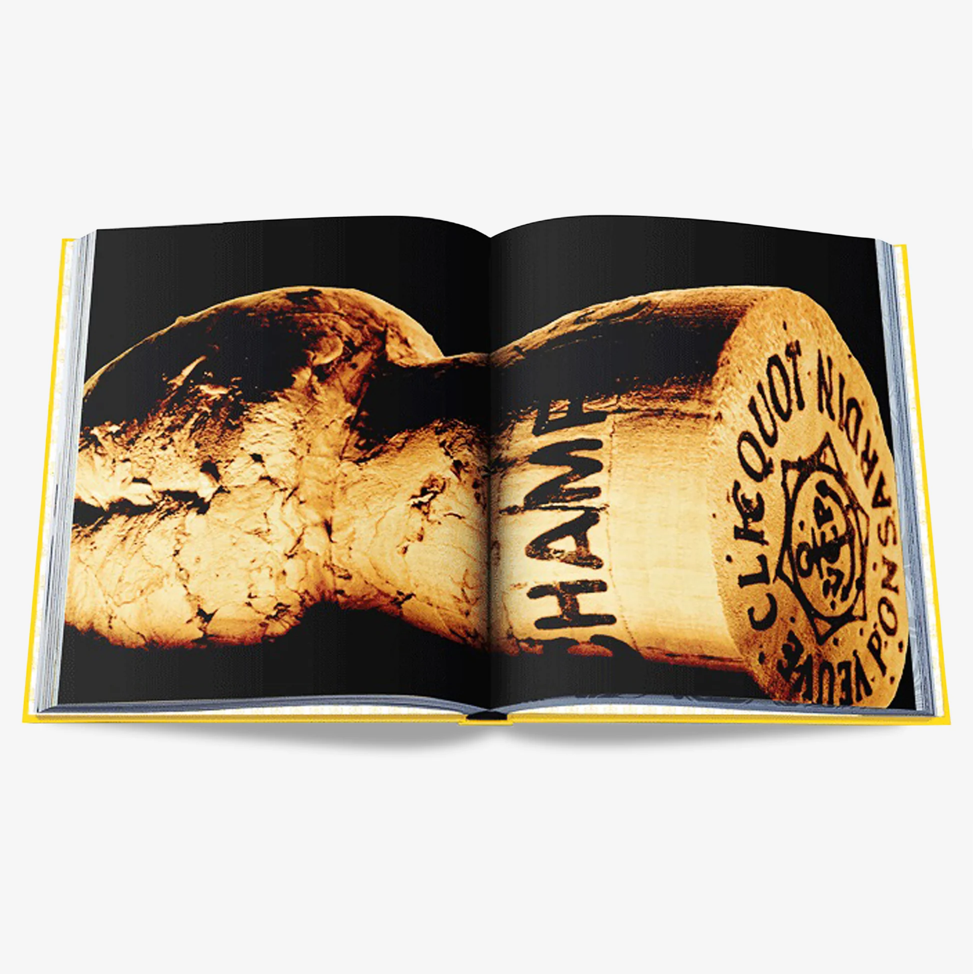 Open Veuve Clicquot book with yellow spine, showing a close-up of a champagne cork on black pages.