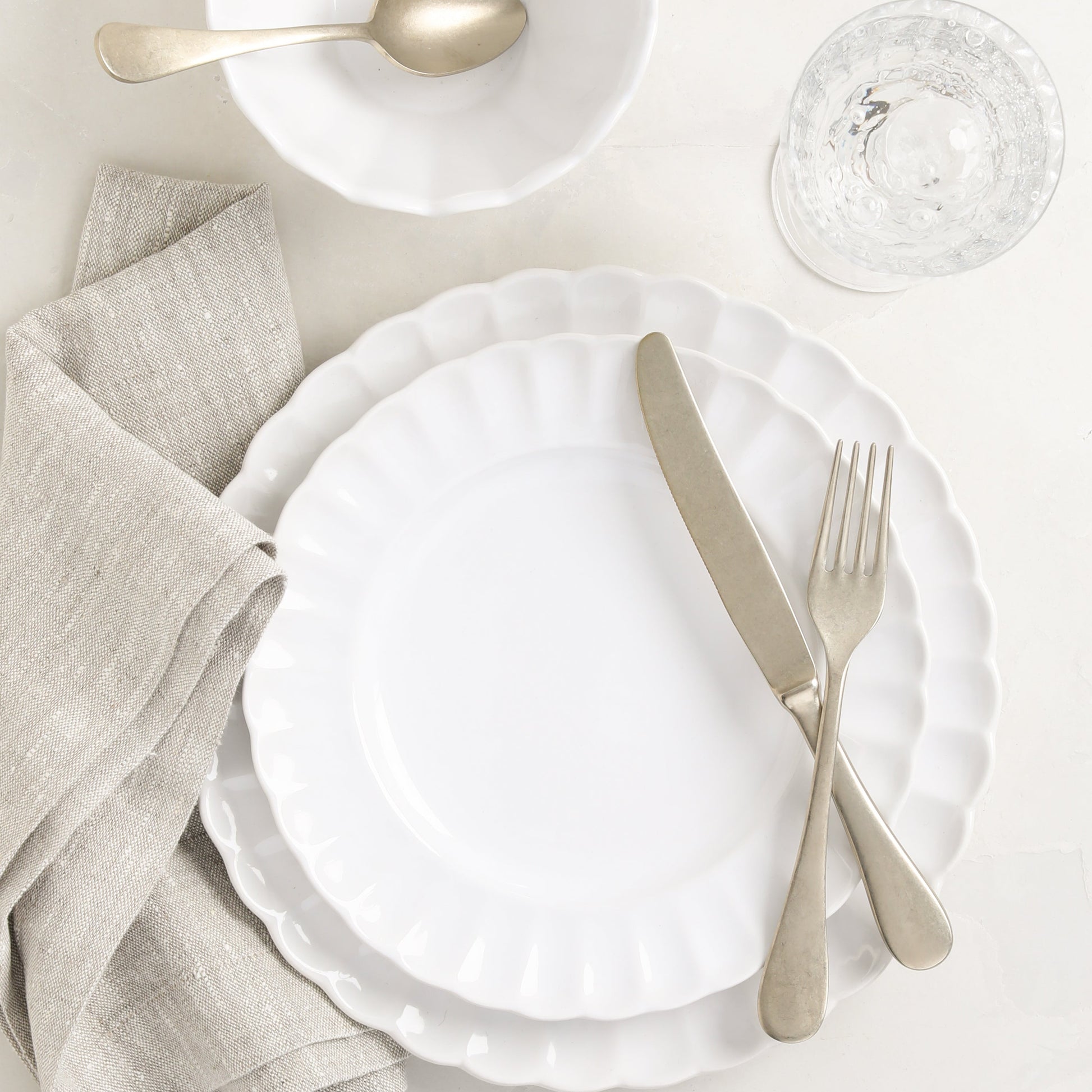 Vintage Champagne 5-piece flatware set with neo-baroque design, warm silvery-champagne finish, on white scalloped plates.